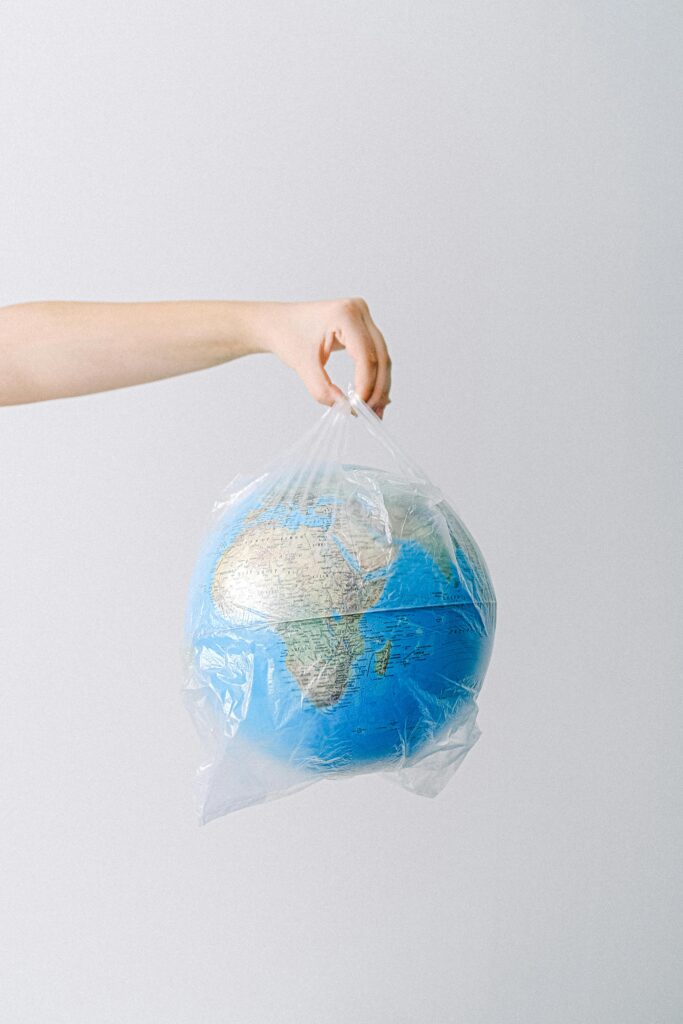 Image of hands holding a globe wrapped in plastic, symbolizing environmental issues.